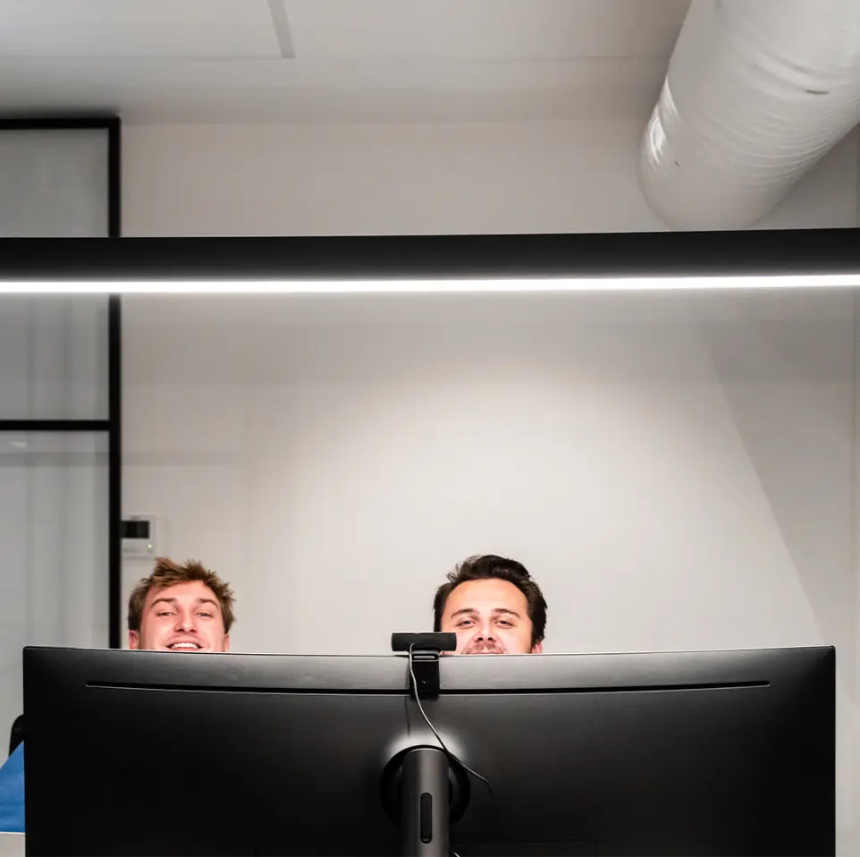 Twee collega's die boven hun scherm kijken