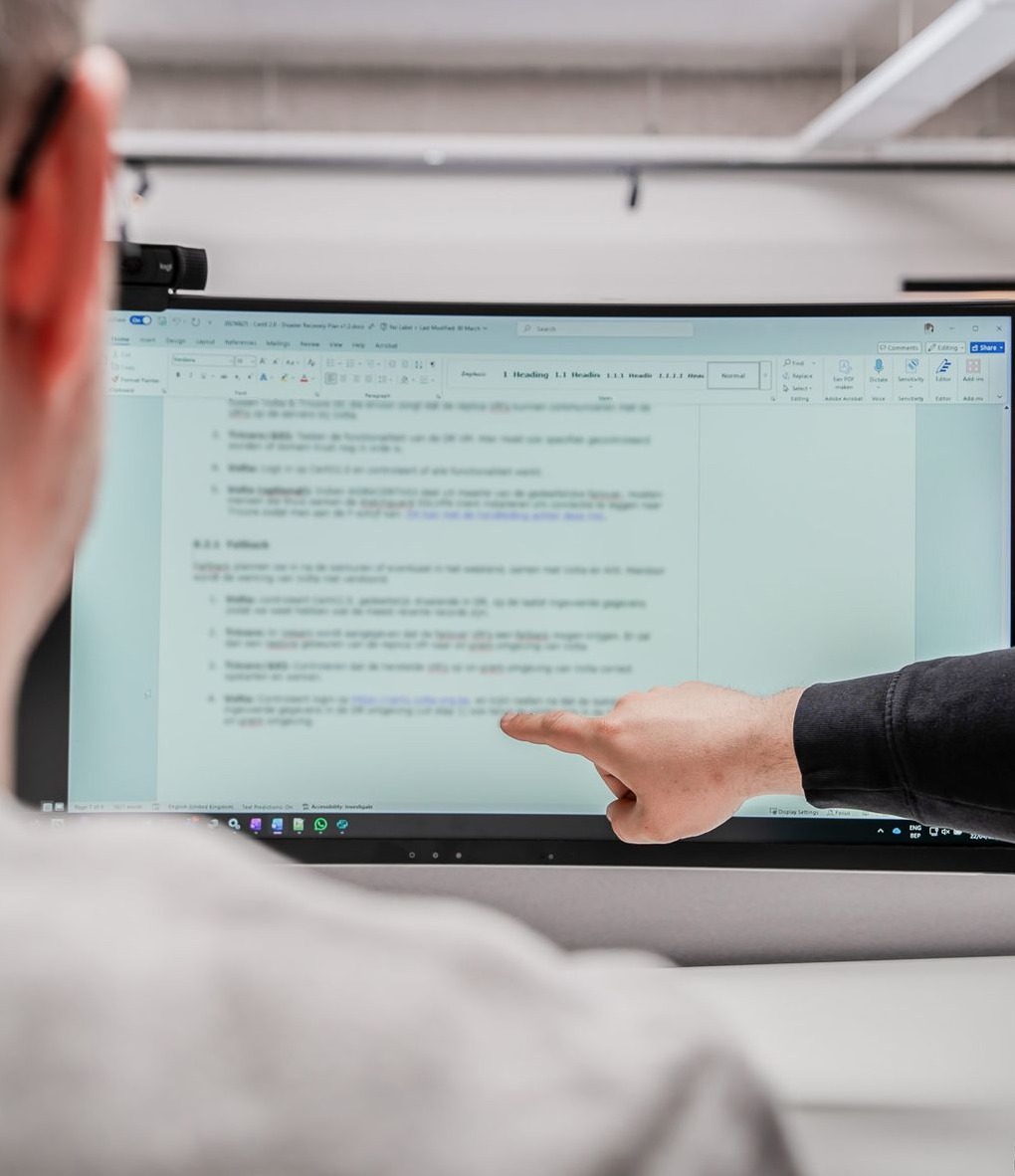 twee collega's aan een scherm, de ene wijst iets aan